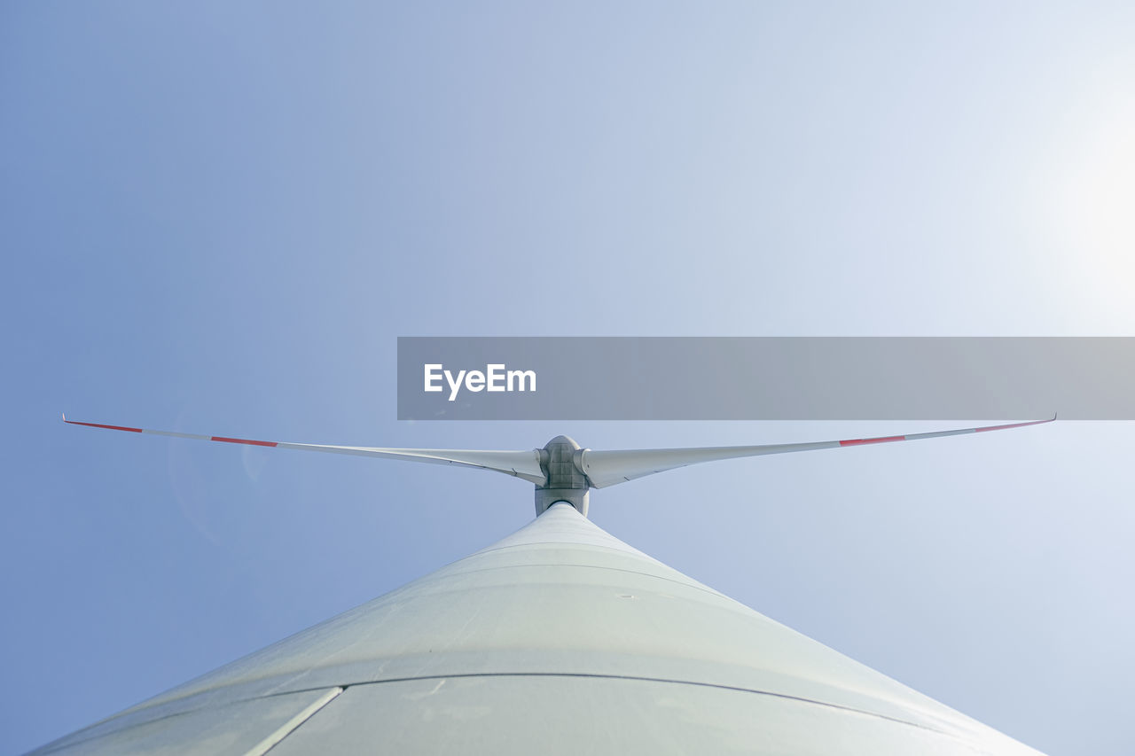 Low angle view of wind turbine against blue sky