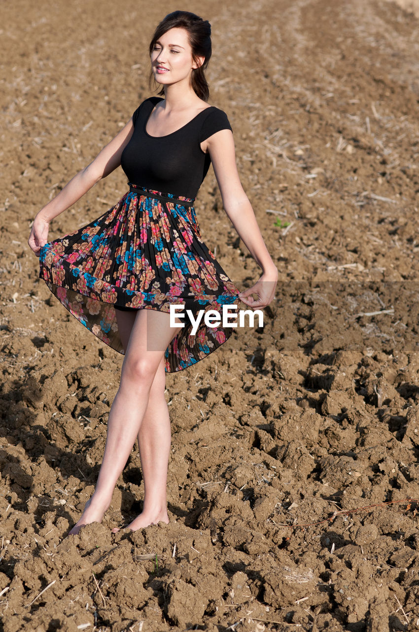 Young woman with dress dancing in field