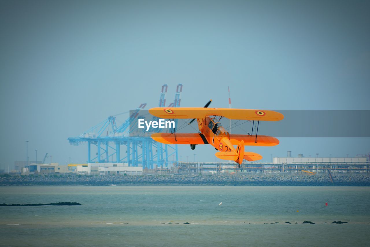 Aircraft flying over sea against clear sky