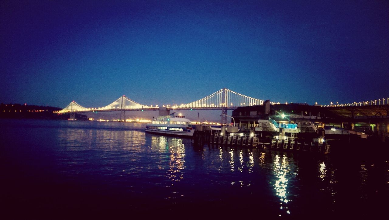 Illuminated bridge over river at night