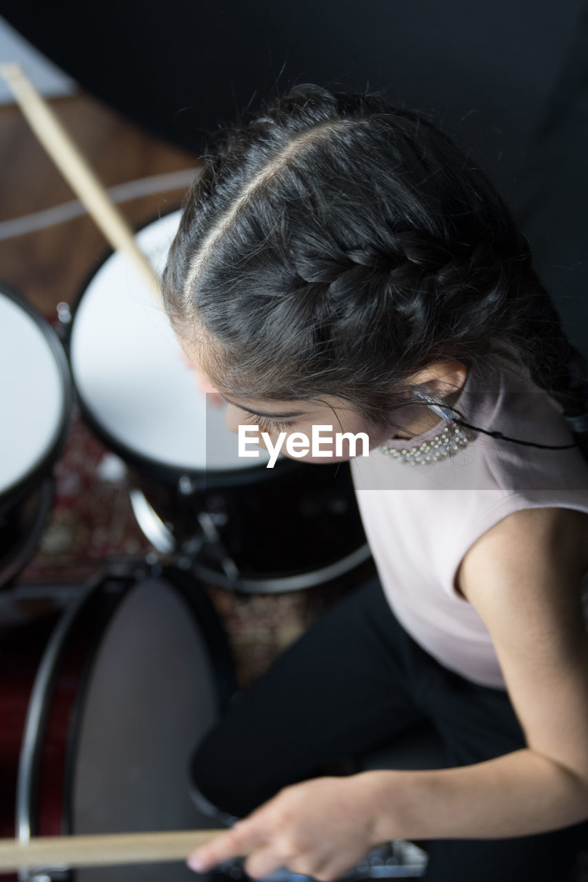 Girl wearing hearing aid while playing drum