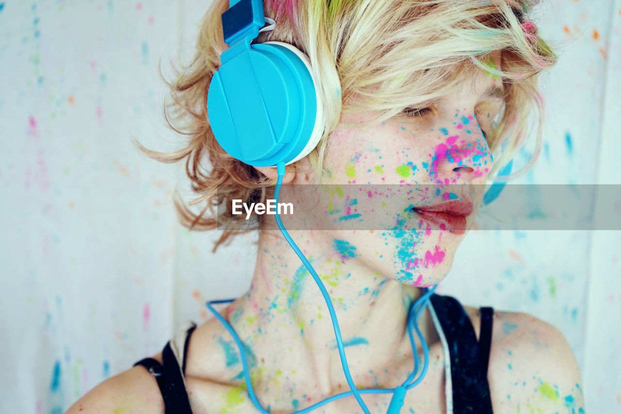 Close-up of woman with powder paint on her face listening music