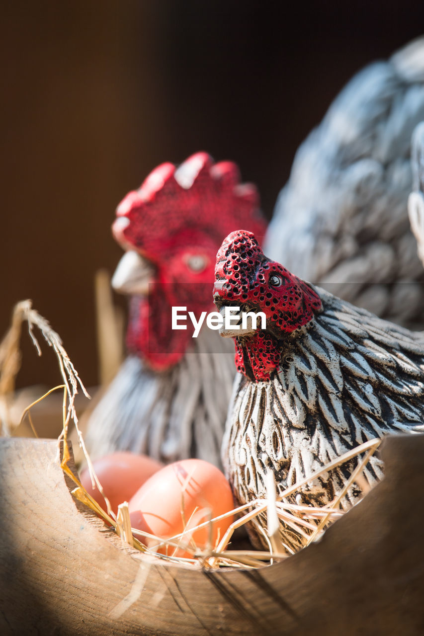 Clay hen and egg in wood basket.