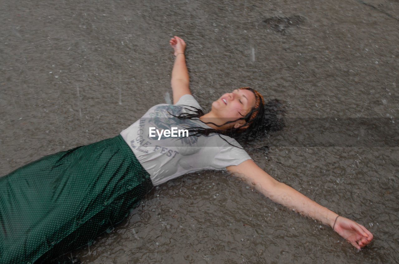 HIGH ANGLE PORTRAIT OF YOUNG WOMAN LYING ON LAND