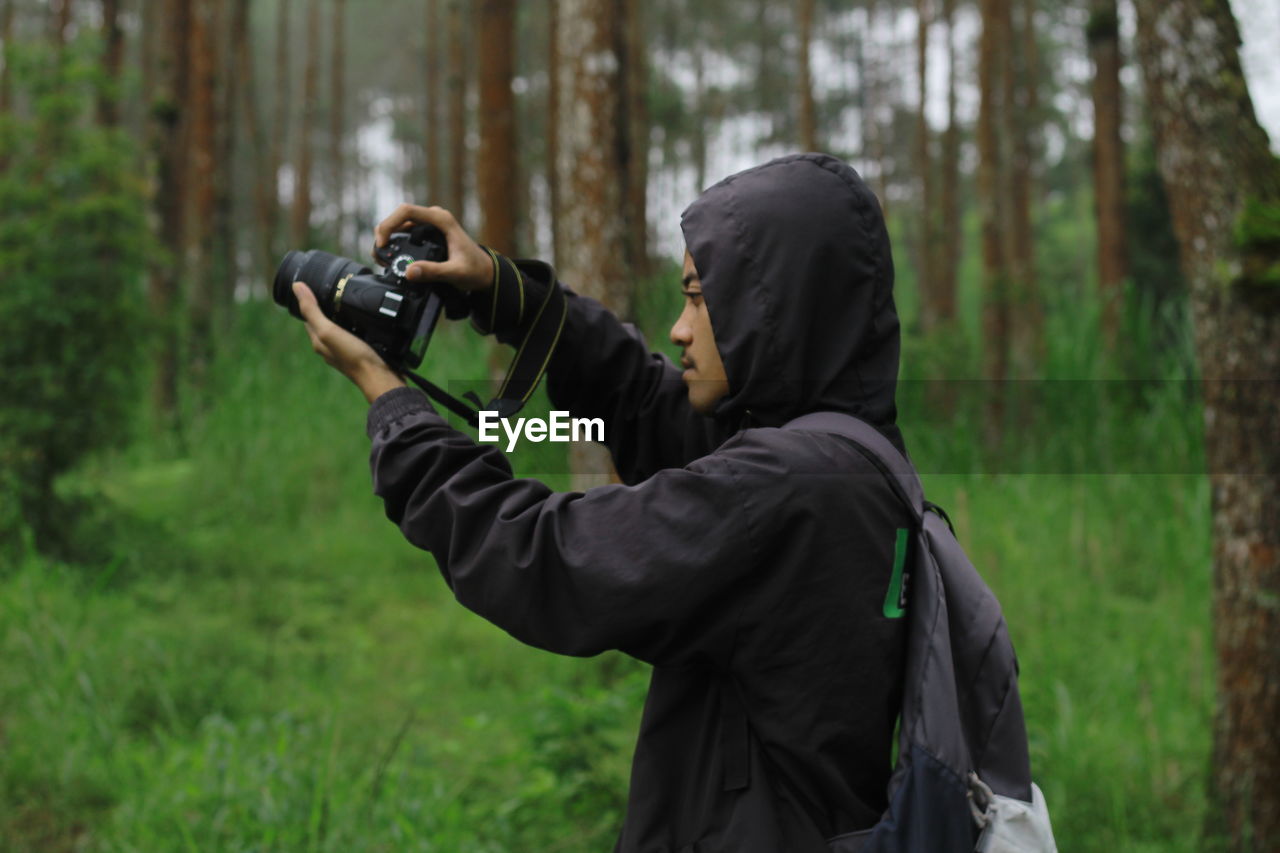 Full length of man photographing in forest