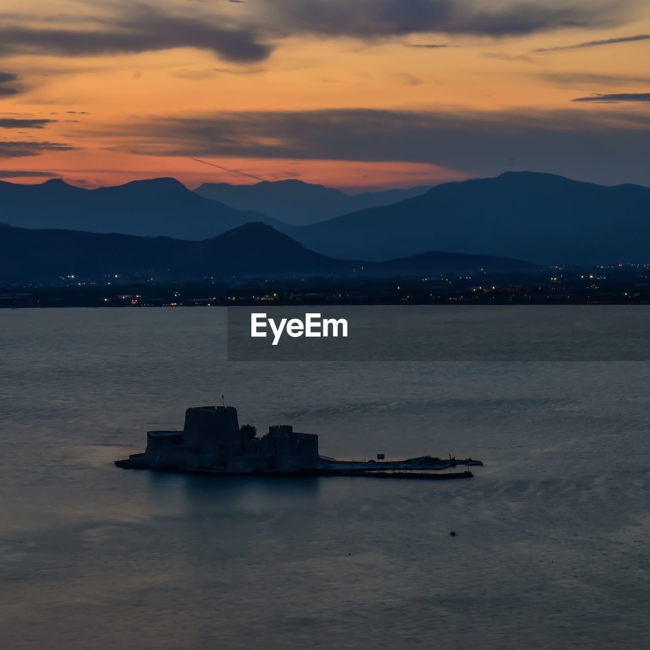 water, sky, mountain, sunset, sea, dawn, cloud, transportation, horizon, nautical vessel, nature, reflection, beauty in nature, scenics - nature, ocean, architecture, bay, mode of transportation, no people, evening, tranquility, mountain range, outdoors, vehicle, travel destinations, coast, ship, tranquil scene, travel, land, built structure, city, silhouette, dramatic sky, harbor, afterglow