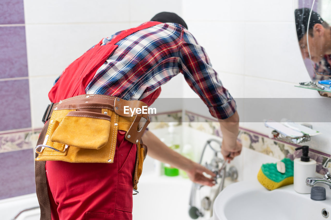 Plumber at work in a bathroom, plumbing repair service, assemble and install concept.