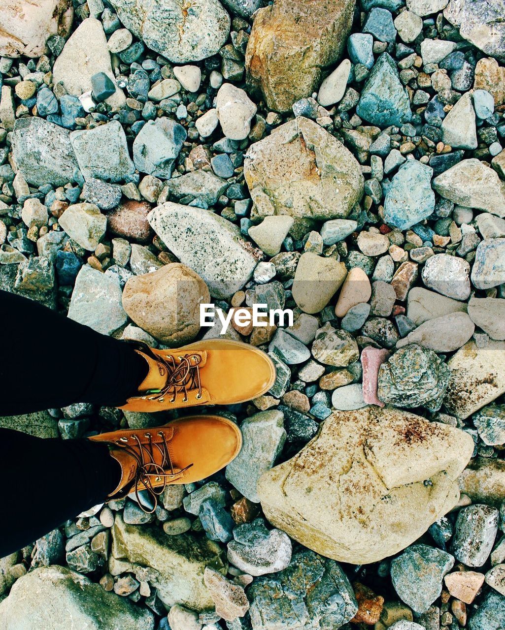 LOW SECTION OF MAN STANDING BY PEBBLES