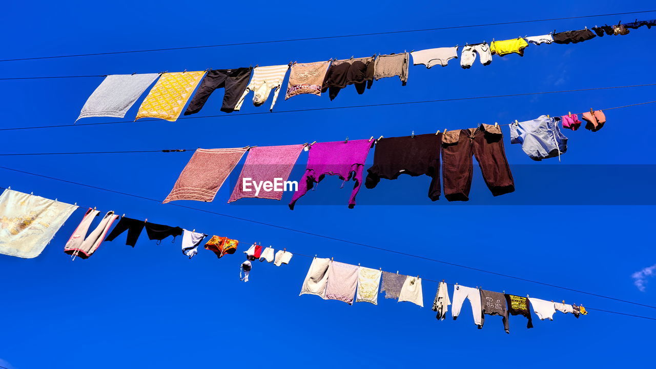 LOW ANGLE VIEW OF CLOTHES DRYING AGAINST CLEAR SKY