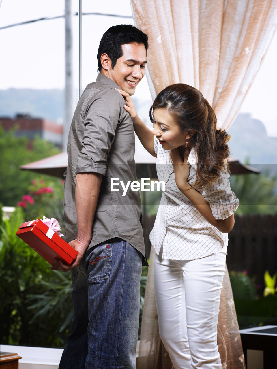 Smiling mid adult woman looking at man with gift at home