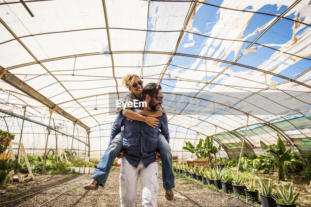Man piggybacking woman in greenhouse
