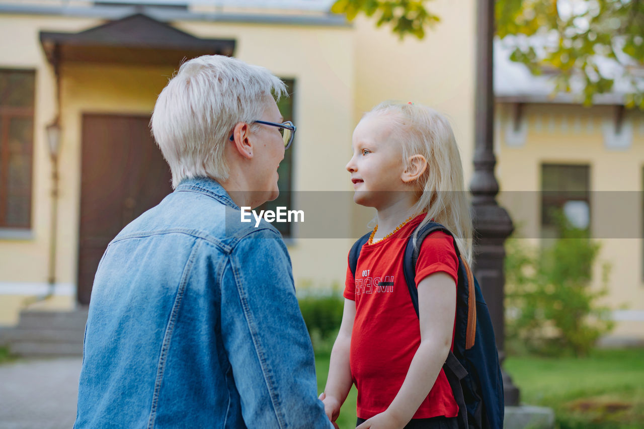 Cute caucasian blonde little girl going to school. mother having a conversation with child,