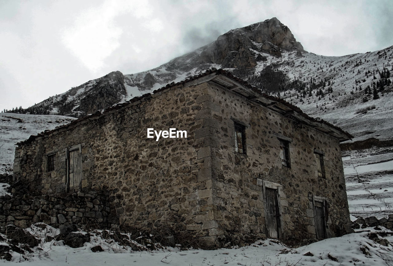Scenic view of snow covered mountains against cloudy sky