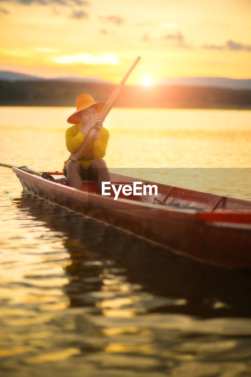 WOMAN IN BOAT AT SEA DURING SUNSET