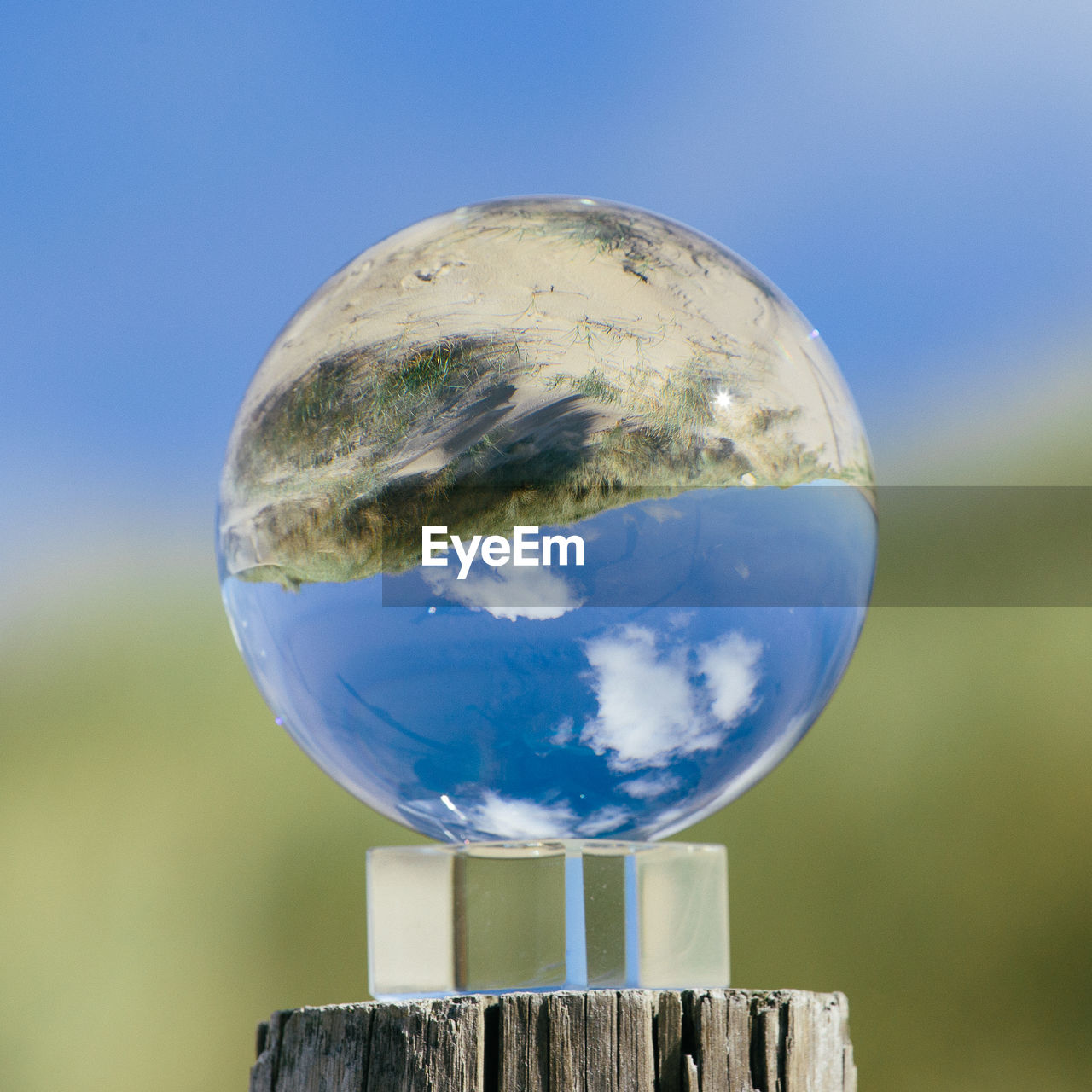 CLOSE-UP OF CRYSTAL BALL AGAINST BLUE SKY WITH WATER