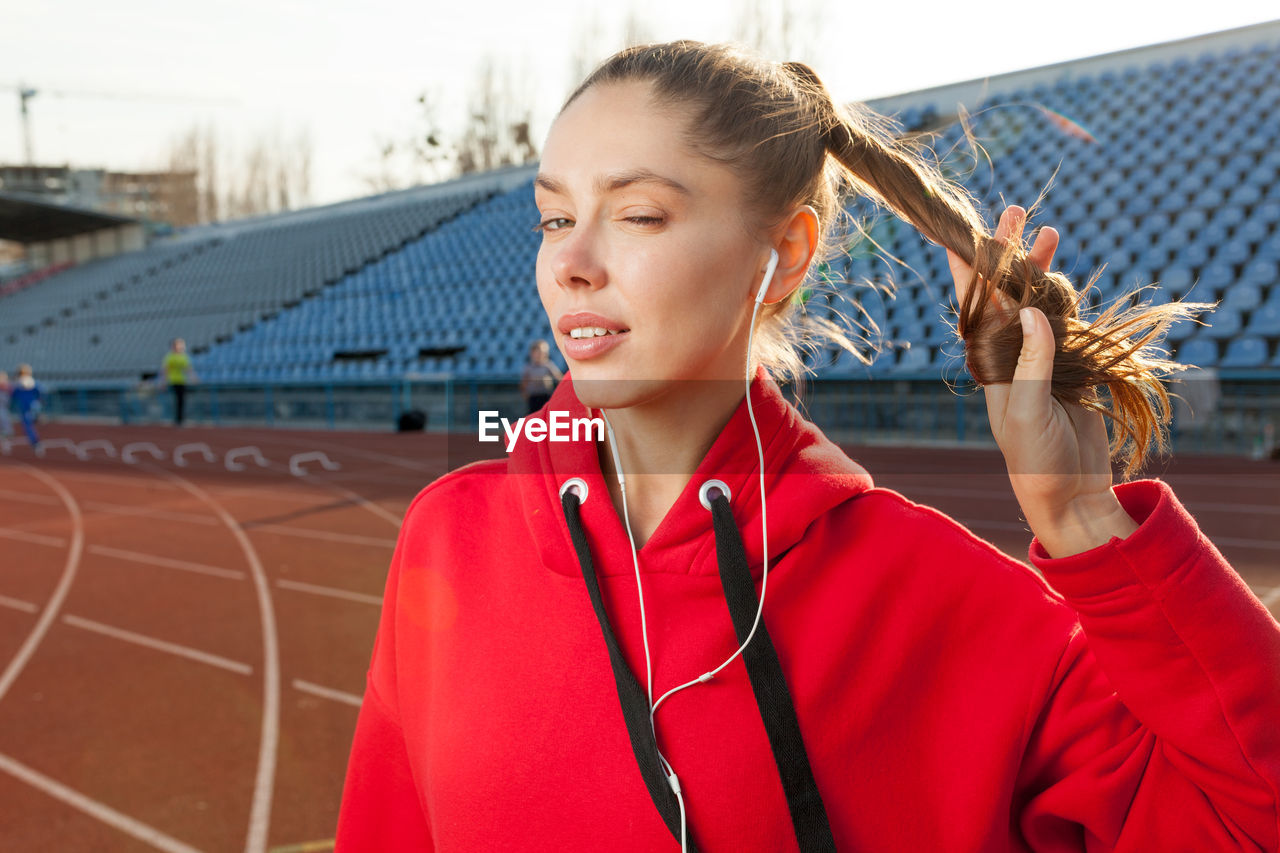 Portrait of young woman winking at stadium