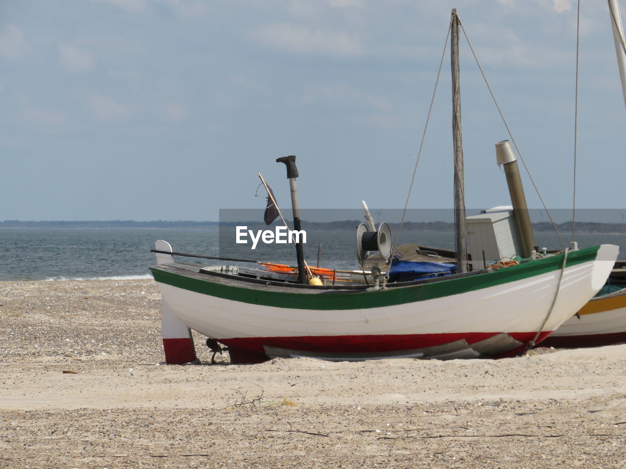 Sailboats moored on beach against sky