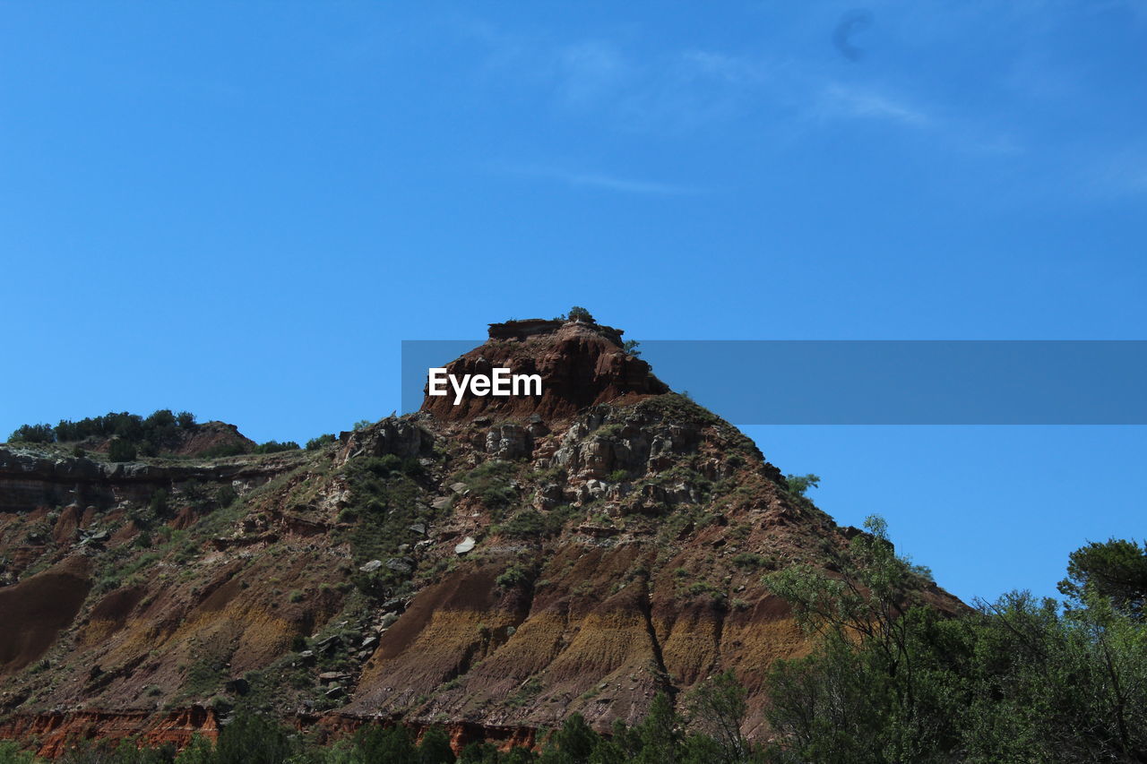 Low angle view of mountain against blue sky