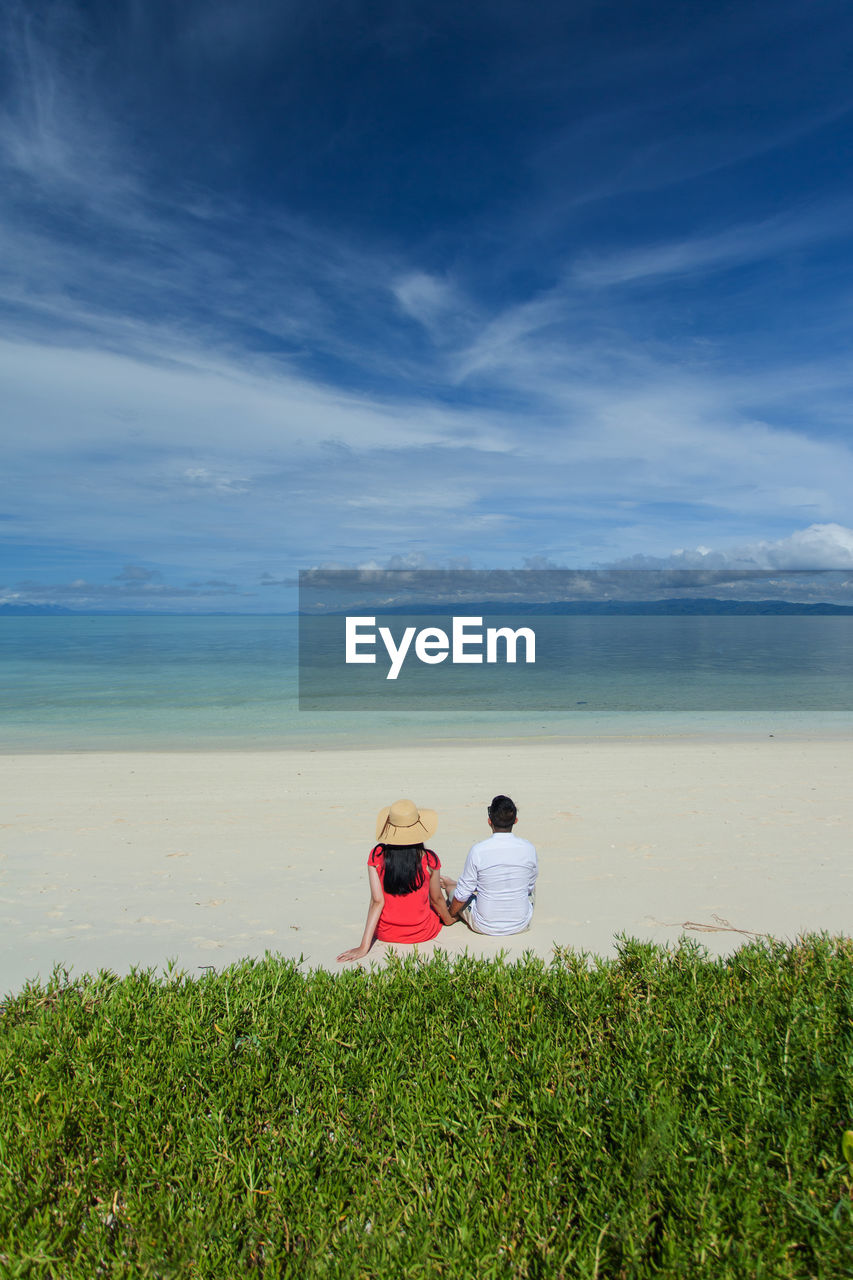 Rear view of couple sitting at beach