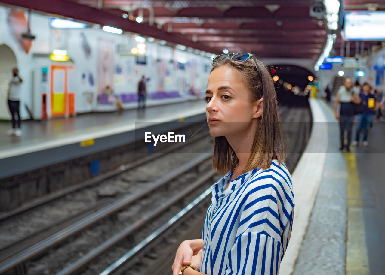 Woman looking away while standing at railroad station