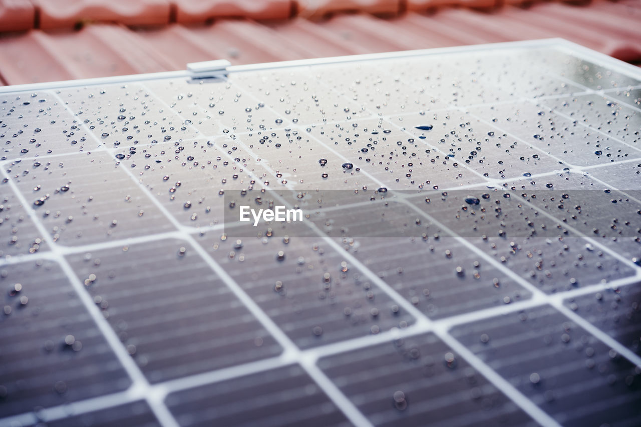 Close up of water drops on solar panel on roof during sunrise.renewable energies and green energy