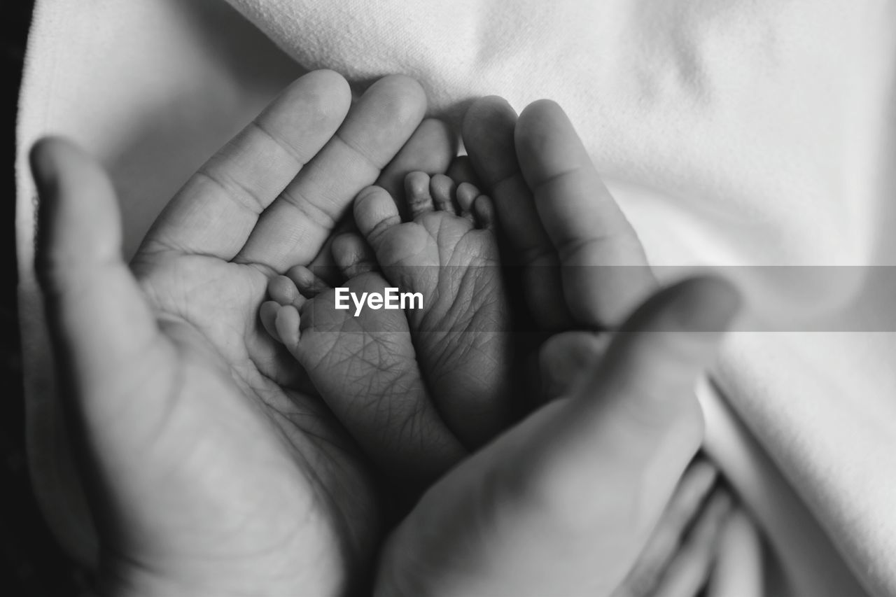 Cropped image of parent holding baby feet