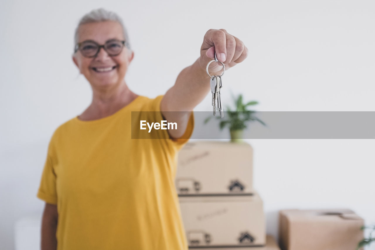 Portrait of smiling woman holding key at home