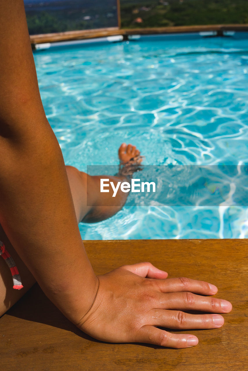 Low section of woman relaxing in swimming pool