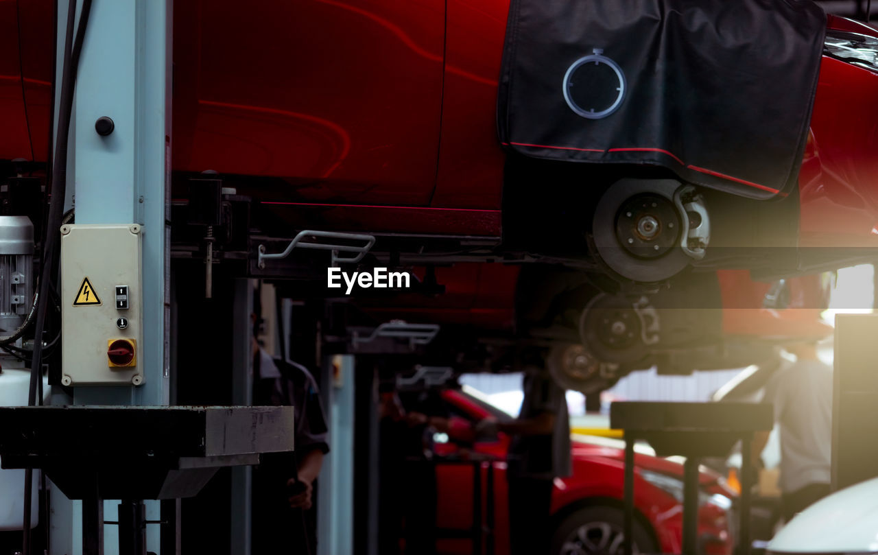 Selective focus on lift in auto repair shop. red suv car lifted in the garage for repair.