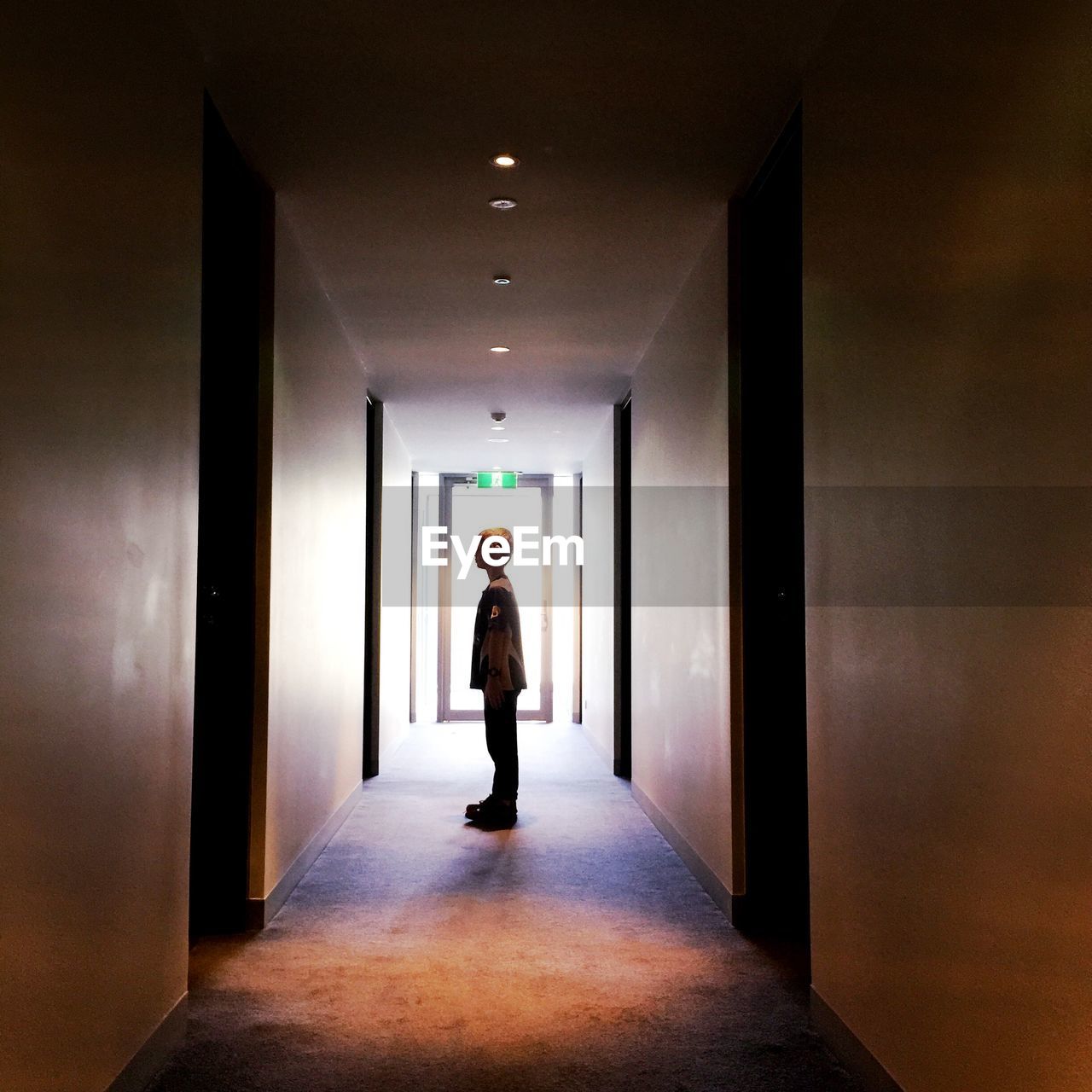 REAR VIEW OF WOMAN WALKING IN CORRIDOR