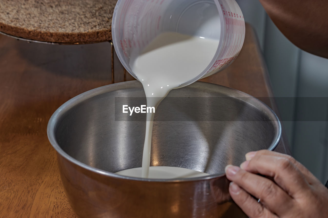 HIGH ANGLE VIEW OF PERSON POURING COFFEE IN CUP