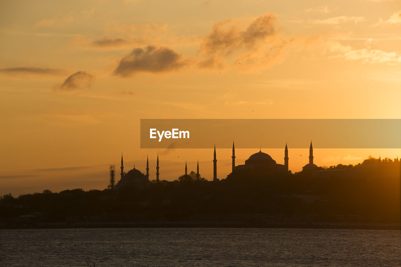 VIEW OF MOSQUE AGAINST BUILDINGS DURING SUNSET