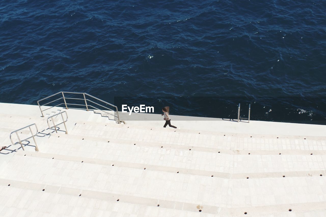 High angle view of a woman jogging on stairs by the river