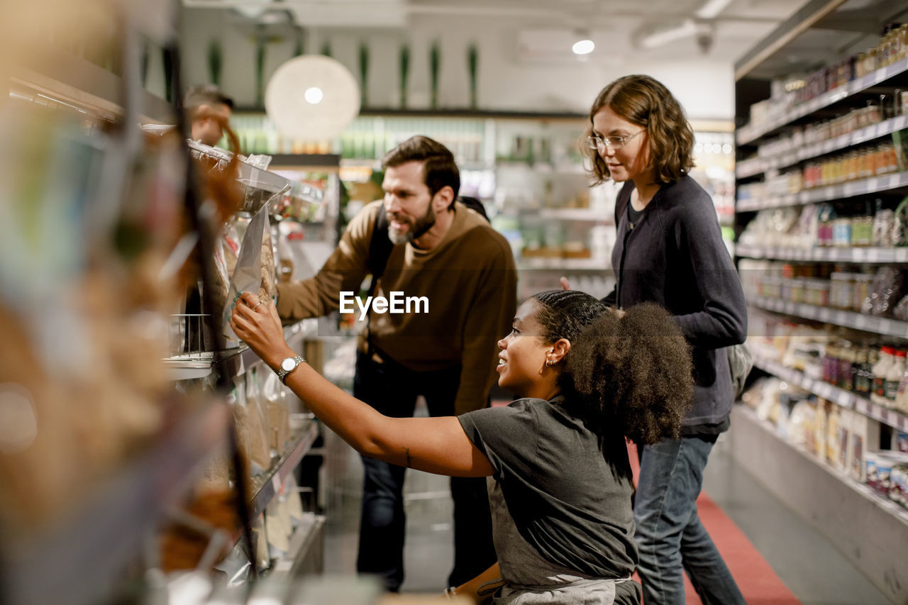 Side view of saleswoman assisting couple while working at supermarket