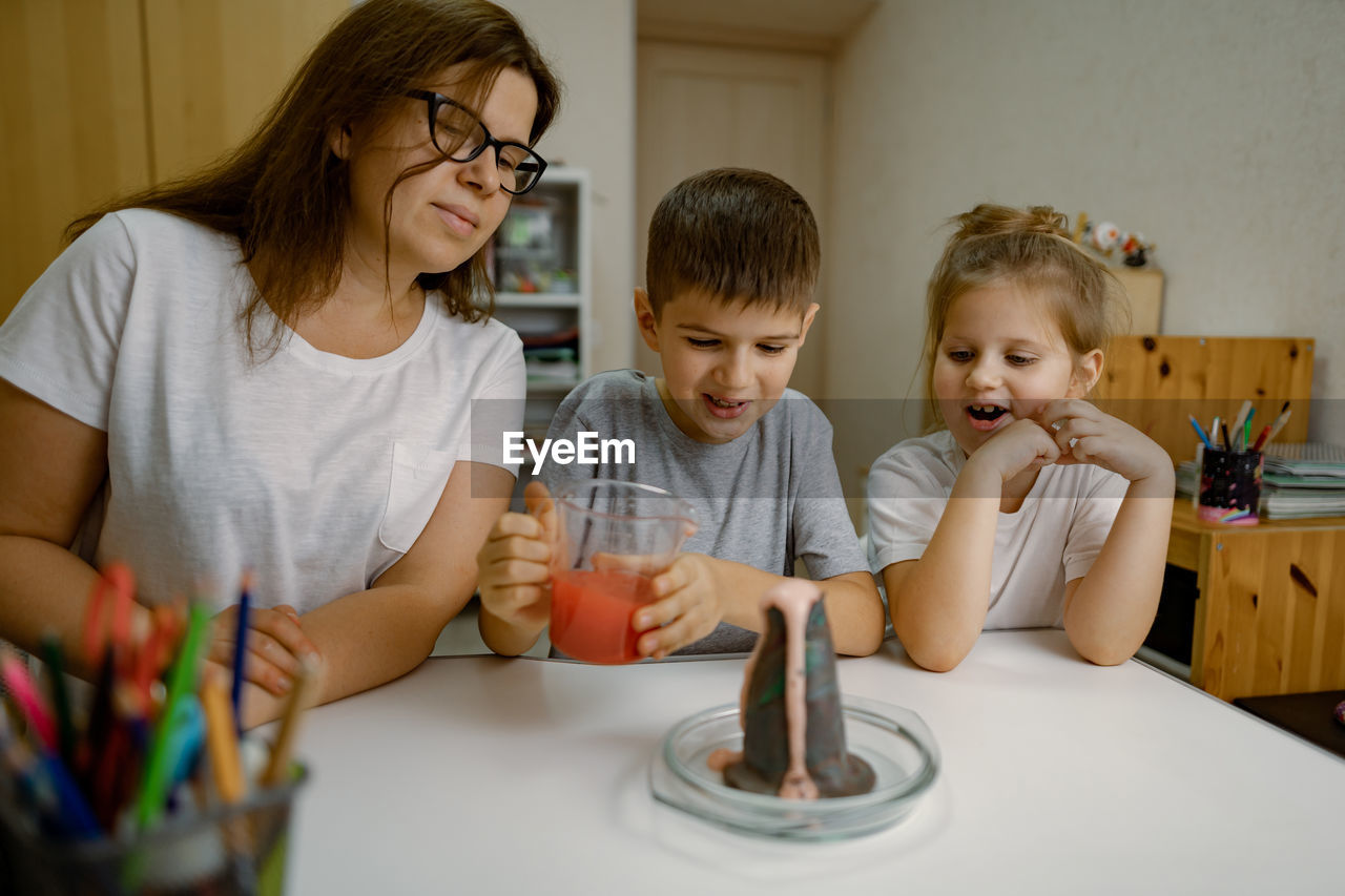 Mom and children at home are conducting an experiment with a volcanic eruption.