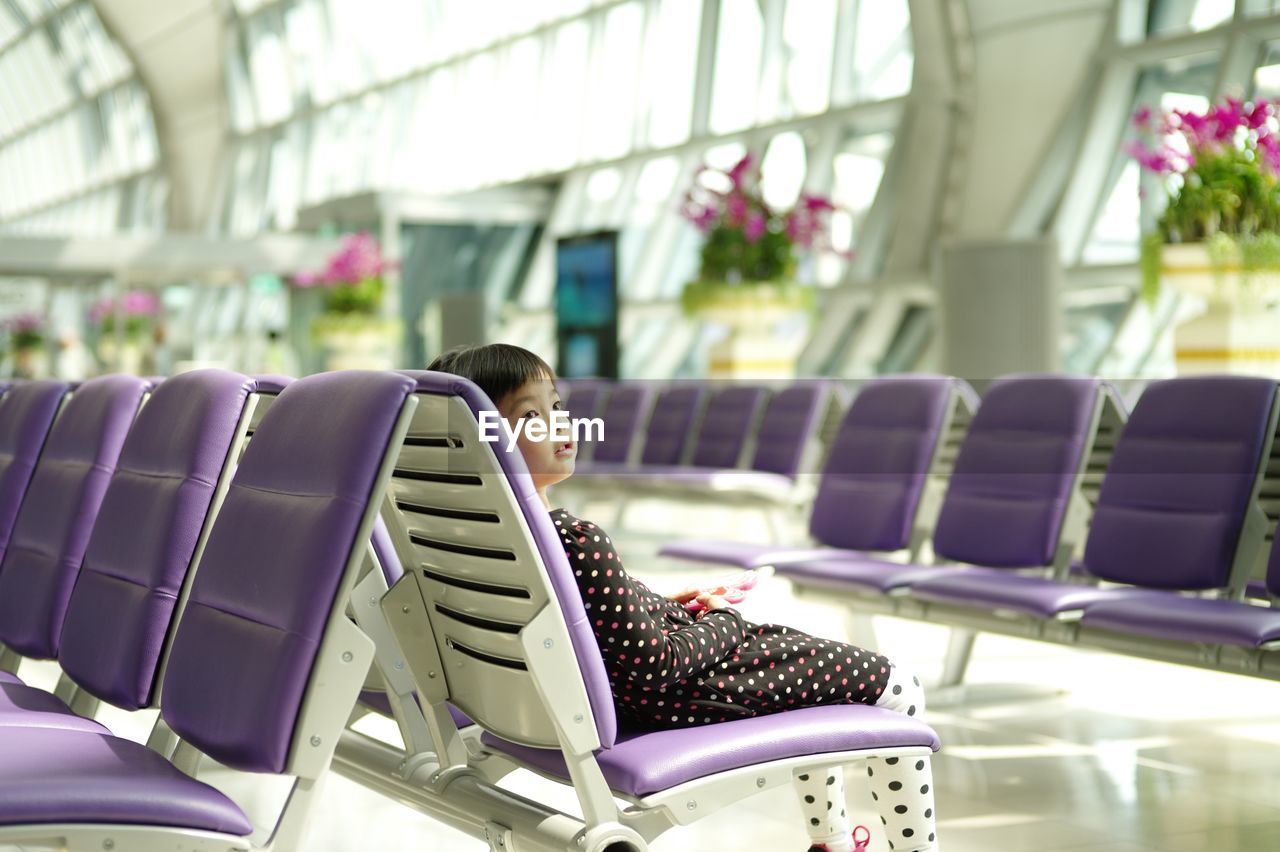 Cute girl sitting on chair at airport