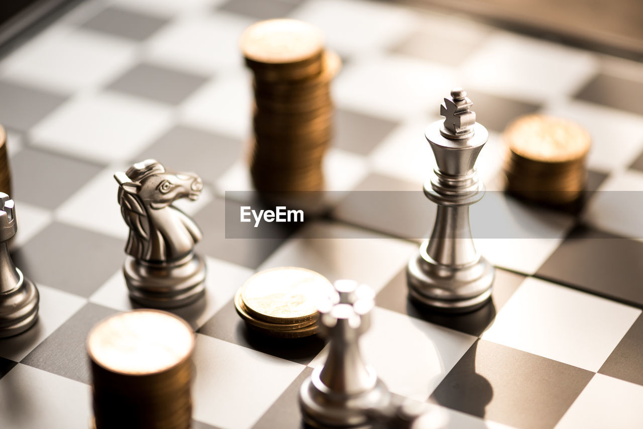 High angle view of chess pieces with coins on board