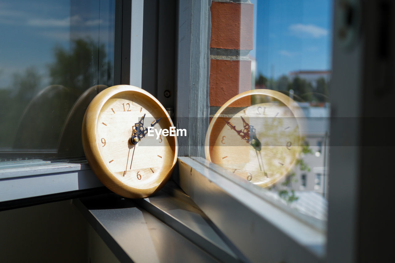 A wooden wall clock sitting on the window