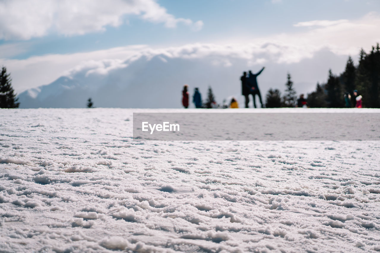People on snow covered land against mountain and sky