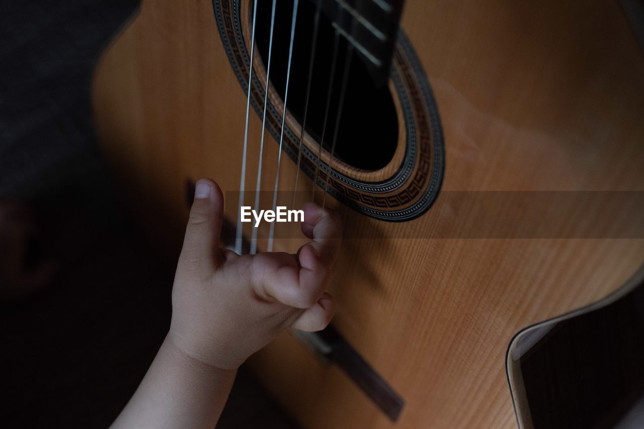 Cropped hand of baby boy on guitar