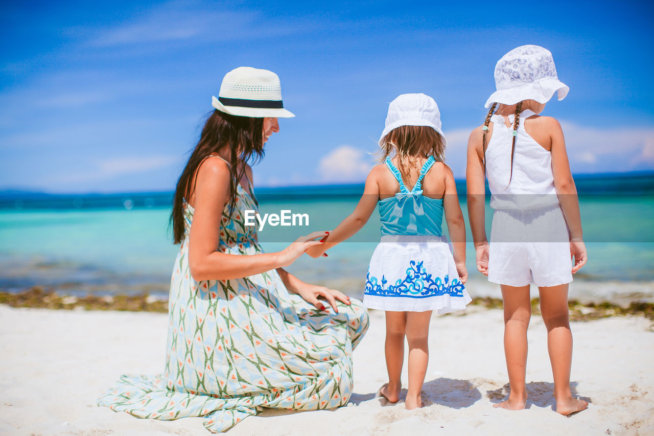 Mother and daughters on beach against sky