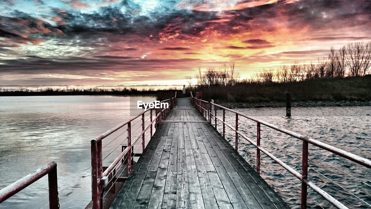 Bridge on river against cloudy sky