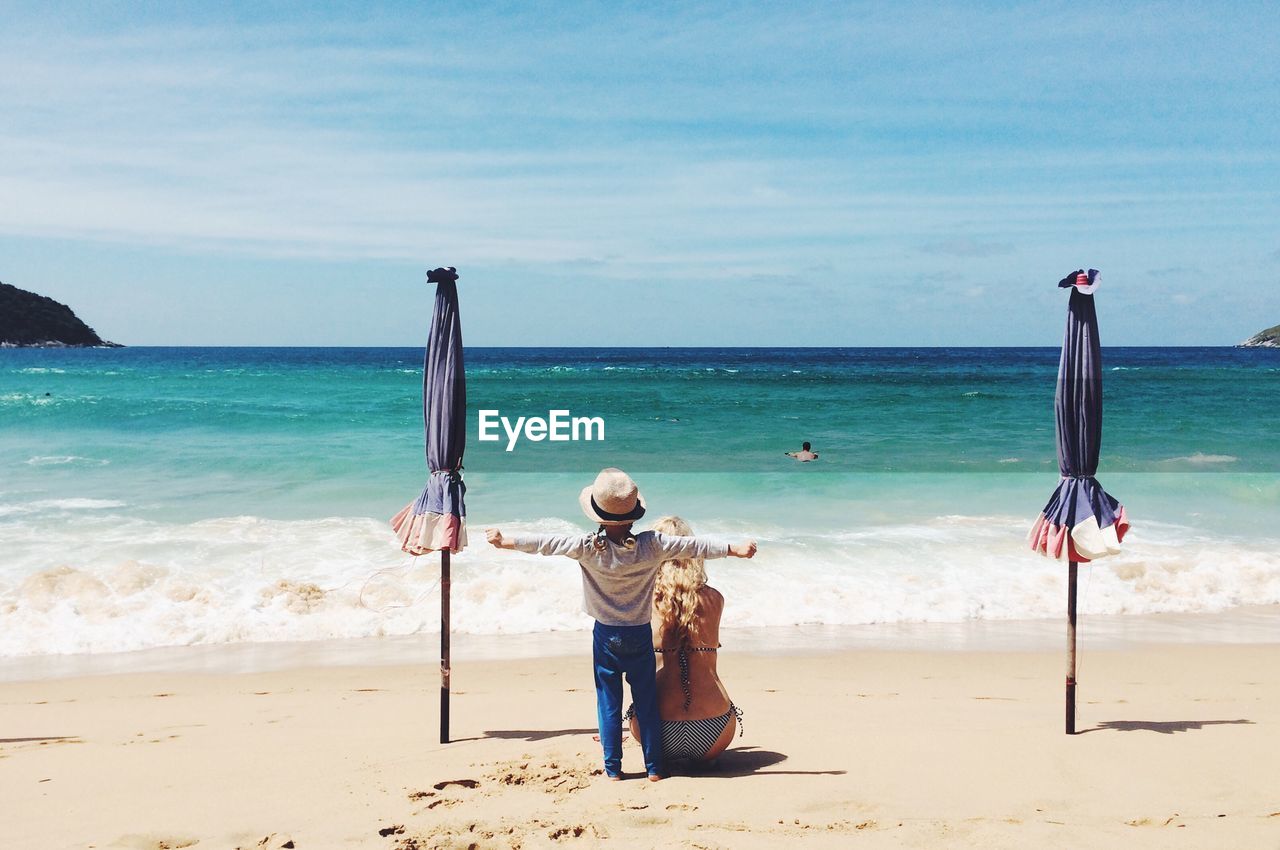 Rear view of people at beach against sky