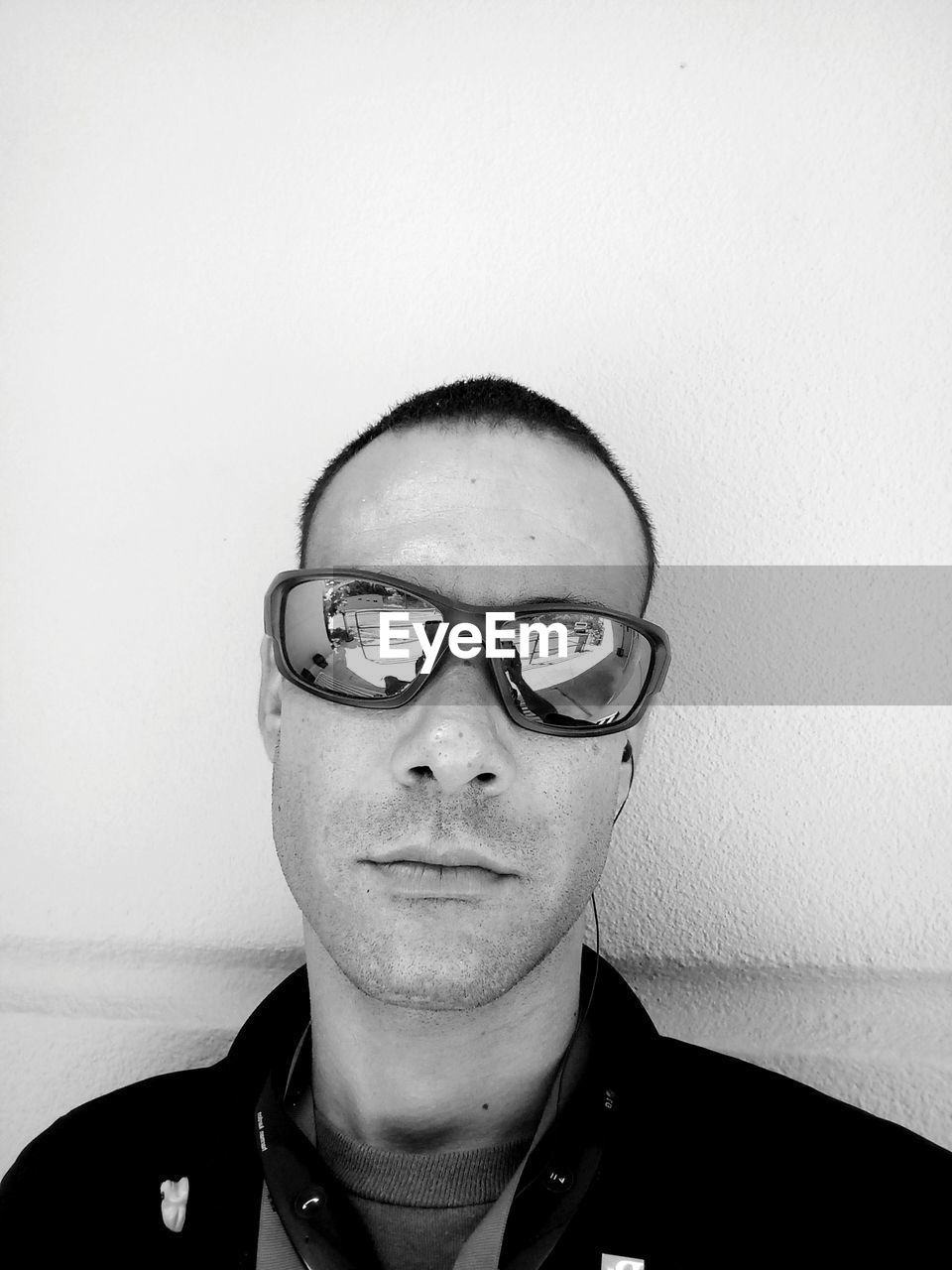 CLOSE-UP PORTRAIT OF YOUNG MAN WEARING EYEGLASSES AGAINST WALL