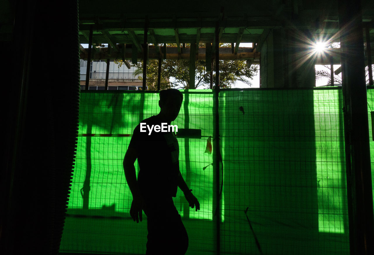 Man walking by green window