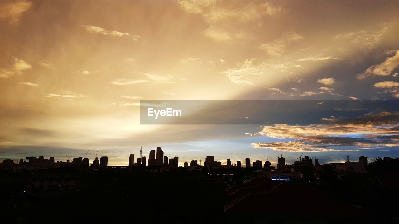 Silhouette of buildings against cloudy sky