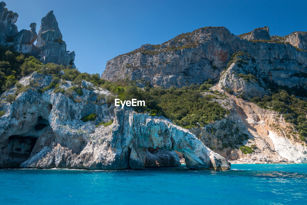 Rock formations by sea against blue sky