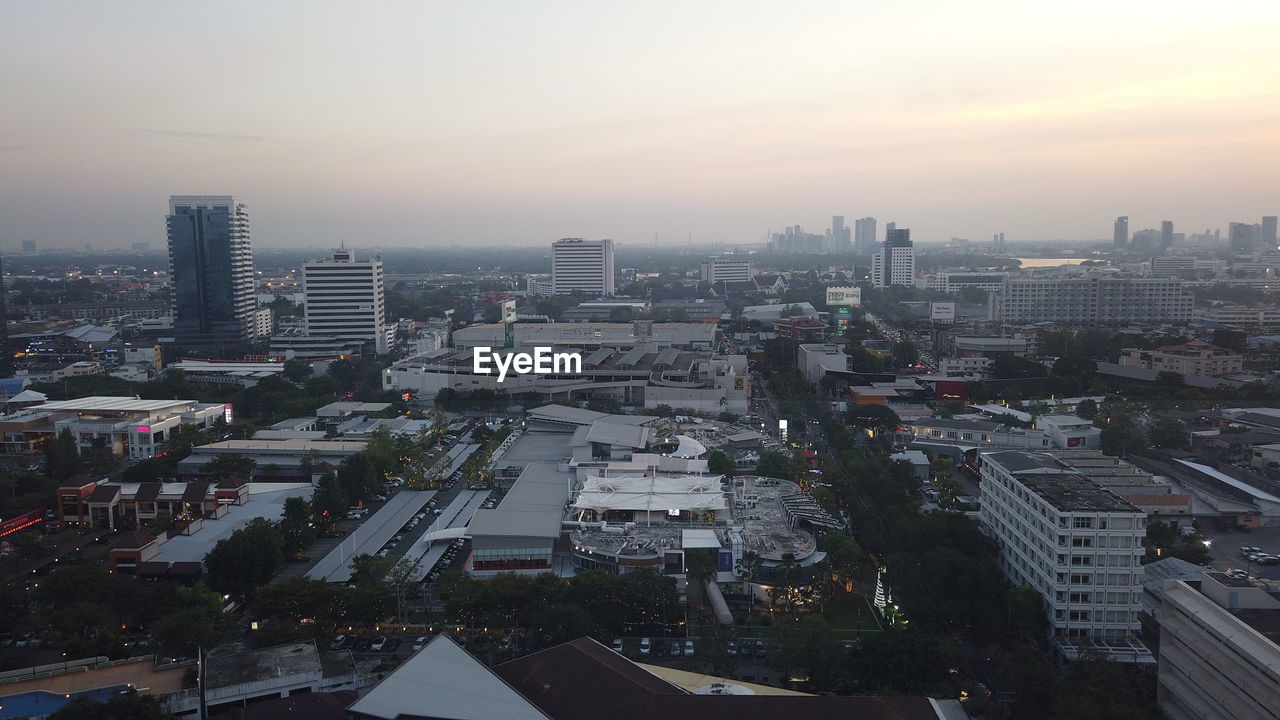 HIGH ANGLE VIEW OF BUILDINGS AGAINST SKY AT SUNSET