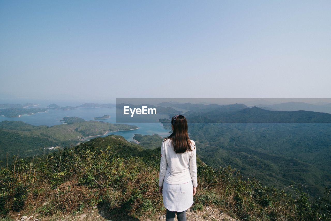 Rear view of woman standing on mountain against sky