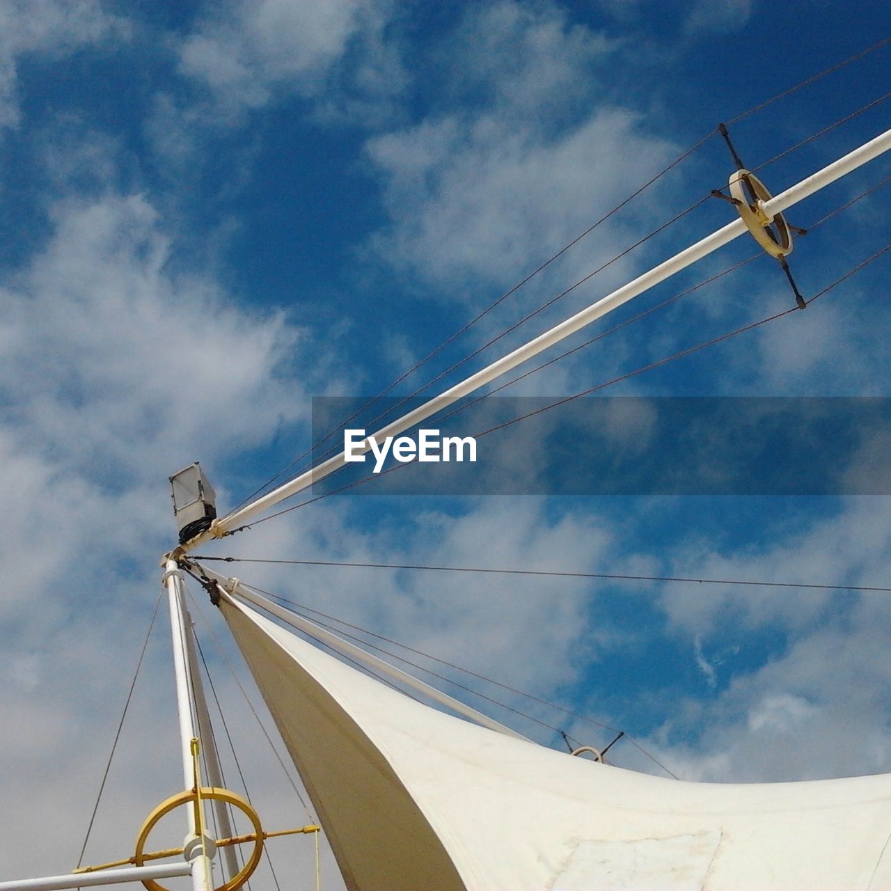 Sail and mast under sky with clouds